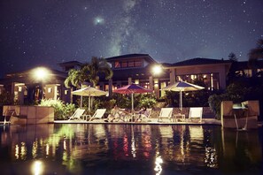 A pool area with lounge chairs and umbrellas, a building with a sign, and a starry night sky. - Hoshino Resorts RISONARE Kohamajima (Taketomi)