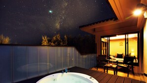A hot tub on a wooden deck with a view of the night sky and a building with a glass door. - Hoshino Resorts RISONARE Kohamajima (Taketomi)