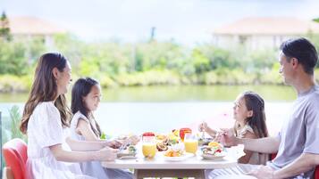 Family enjoys a meal together in a serene outdoor setting with a beautiful view.
