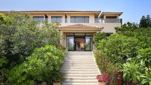 A two-story house with a tiled roof, a balcony, and a staircase leading to the entrance. - Hoshino Resorts RISONARE Kohamajima (Taketomi)