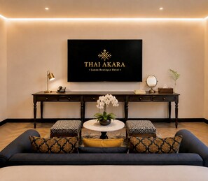 A modern hotel lobby with a sofa, a round table with a vase of flowers, a desk with a telephone, a mirror, and a framed sign. - Thai Akara - Lanna Boutique Hotel (Chiang Mai)