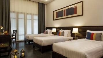A hotel room with two beds, a desk with a lamp, a chair, and a large framed picture on the wall.