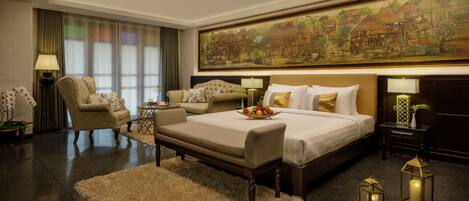 A hotel room with a large bed, a sofa, a chair, a small table, and a painting on the wall.