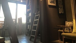 Quarto com uma escada encostada na parede, uma estante de livros e cartazes motivacionais.