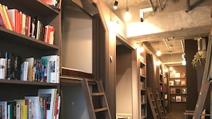 A library with bookshelves, ladders, and a staircase leading to another level. - Book Tea Bed GINZA - Hostel (Tokyo)
