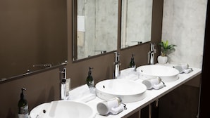 A bathroom with two sinks, a large mirror, a potted plant, and a hairdryer on the counter. - Book Tea Bed GINZA - Hostel (Tokyo)