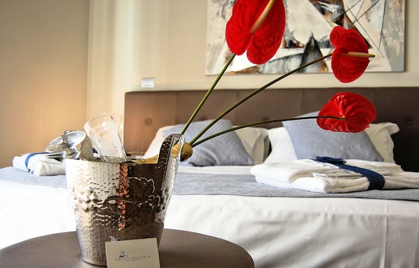 A hotel room with a bed, a vase with red flowers, and a painting on the wall. - I Segreti della Valle (Agrigento)
