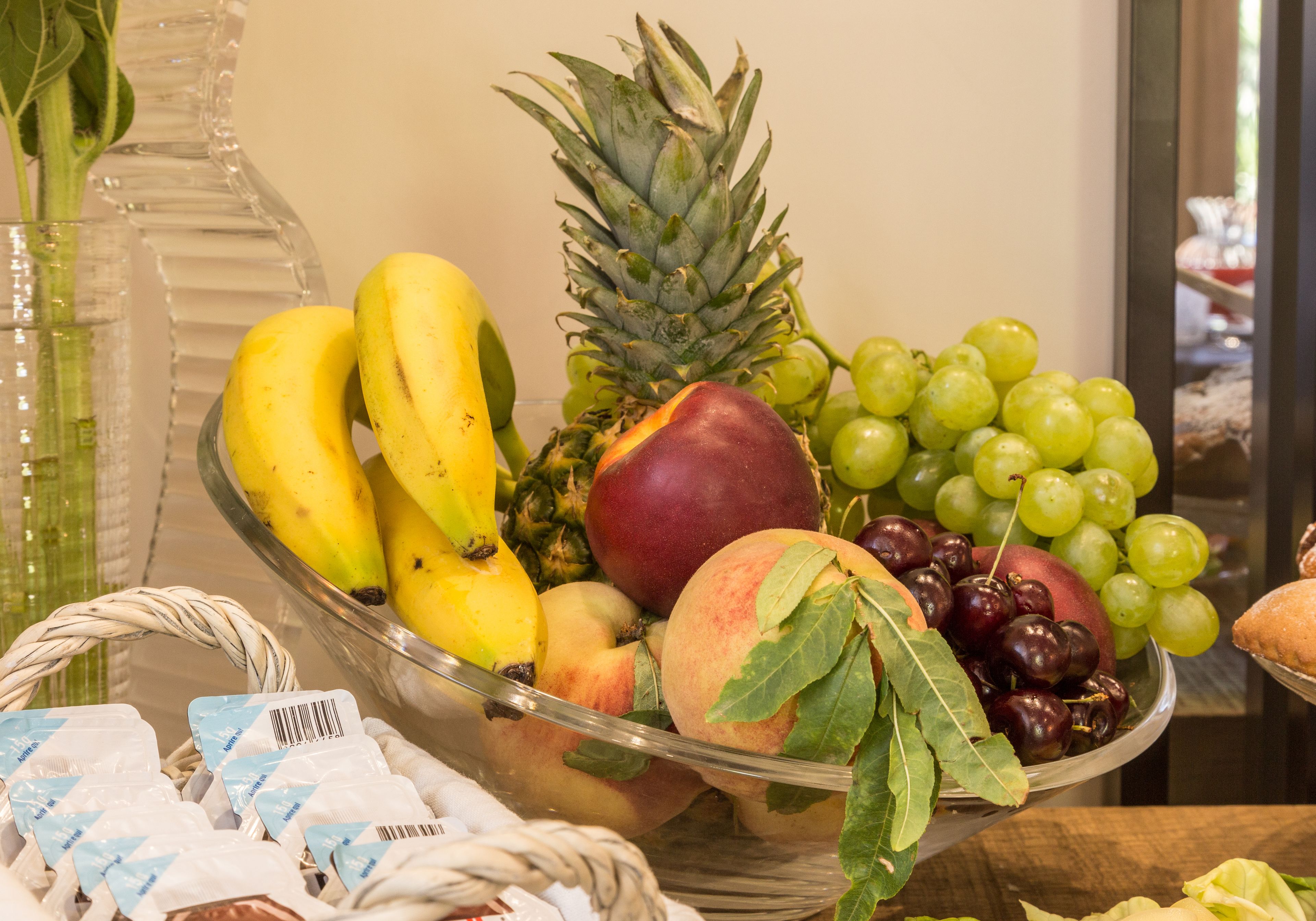 Un frutero con plátanos, piña, uvas y otras frutas.