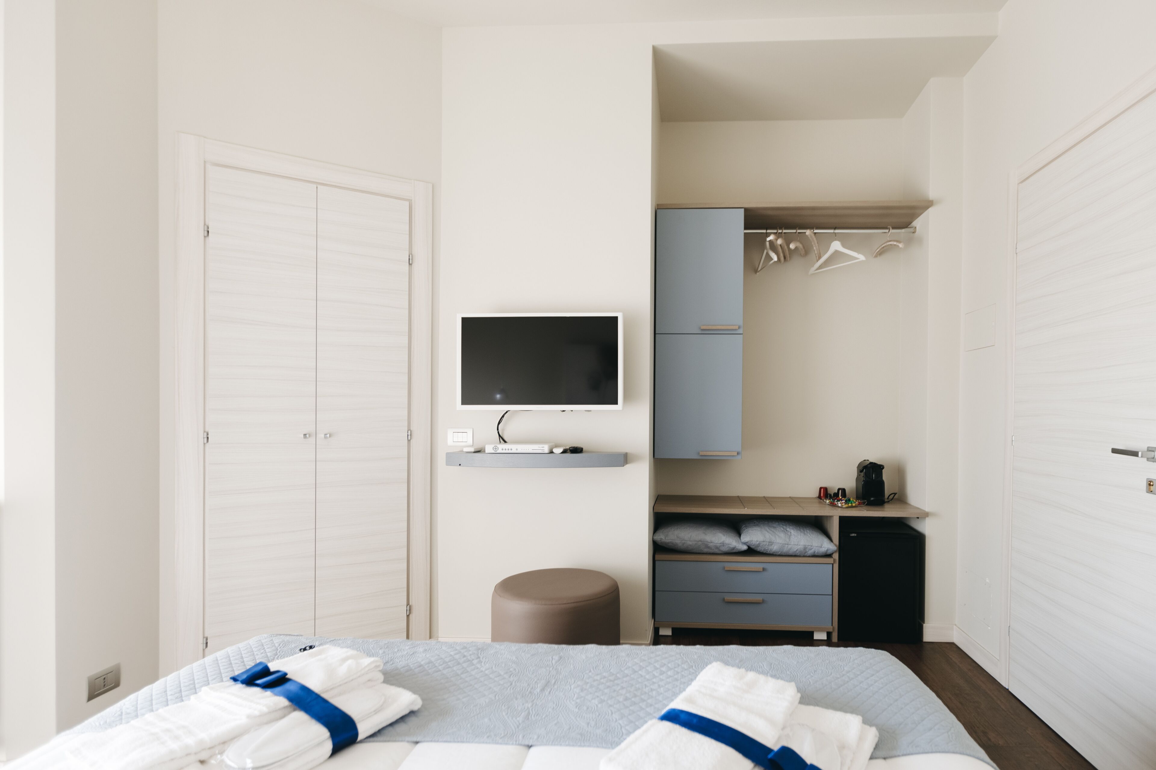 Ein Schlafzimmer mit einem Bett, einem Fernseher, einem Kleiderschrank, einem Schreibtisch und einer kleinen Kommode.