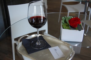 A wine glass on a tray with a card, a red rose, and a small plant on a table. - I Segreti della Valle (Agrigento)