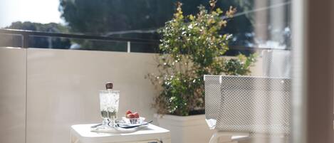A balcony with a table set for two, a potted plant, and a chair.
