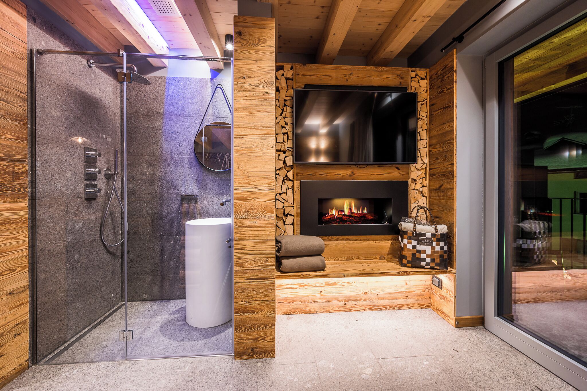 Un baño moderno con ducha de vidrio, lavamanos blanco y chimenea empotrada.