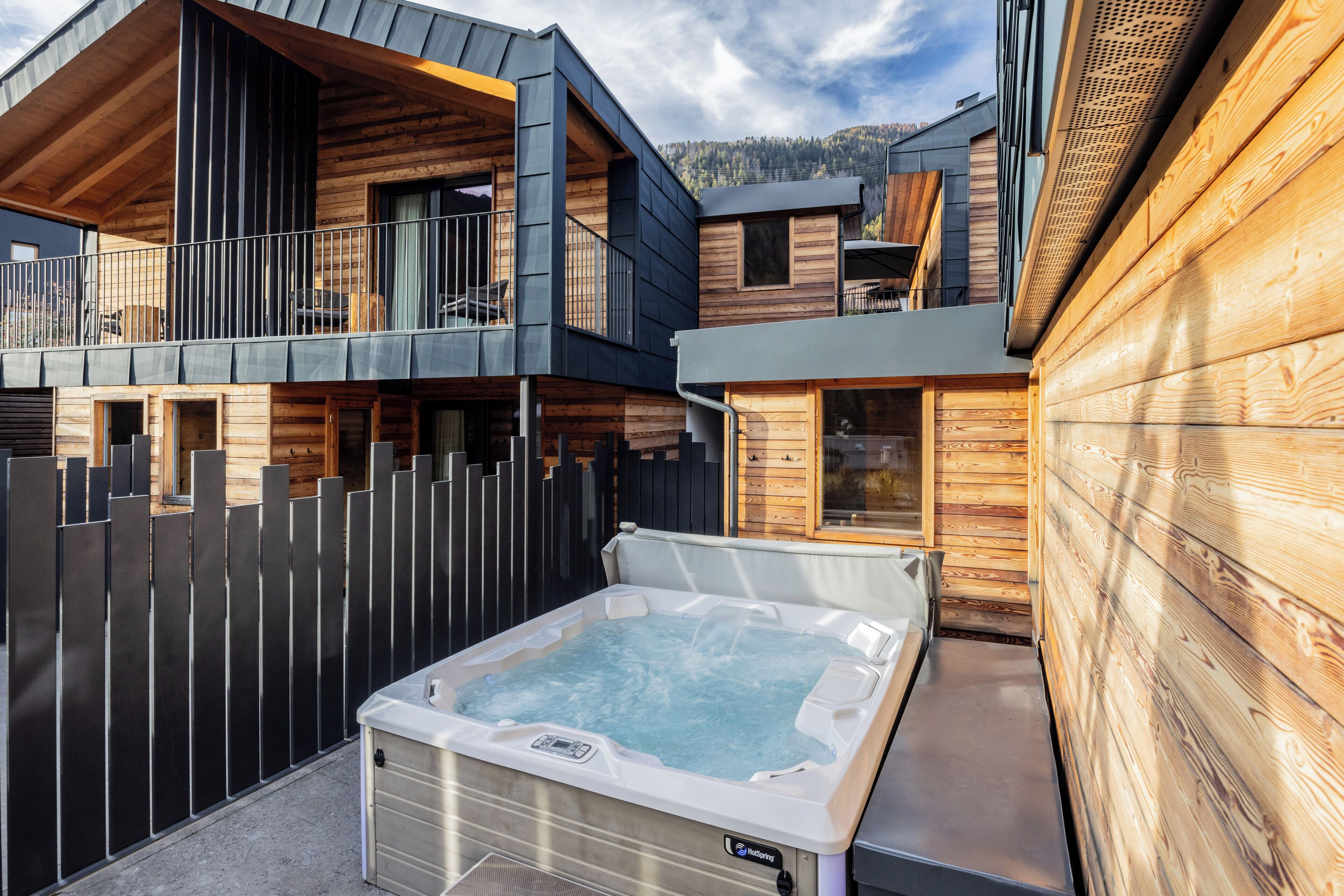 A modern wooden cabin with a hot tub in the backyard.