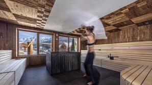 Una sauna amb parets i bancs de fusta, un finestral gran amb vistes a les muntanyes i un sostre de fusta.