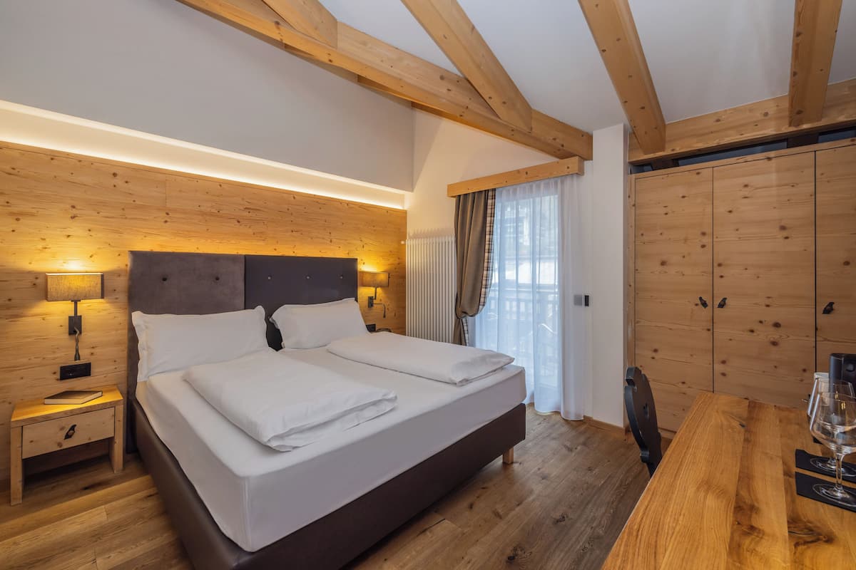 Une chambre avec un grand lit, une tête de lit en bois, une table de chevet et une armoire en bois.