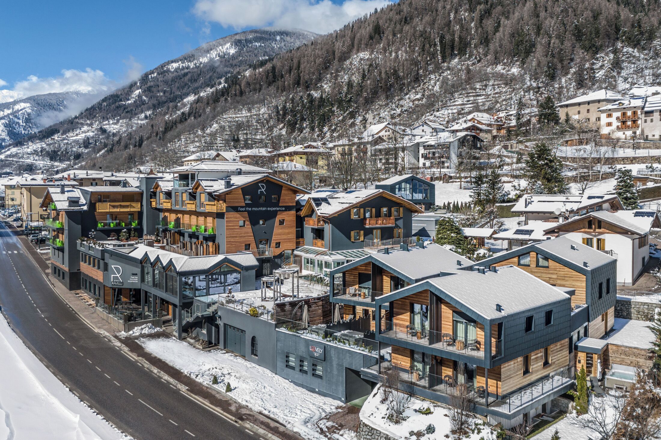 A modern hotel with a mix of wooden and contemporary architecture, located in a snowy mountainous area.