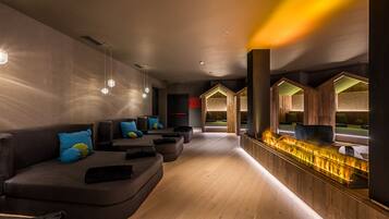 A modern lounge area with a wooden reception desk, seating with cushions, and pendant lighting.