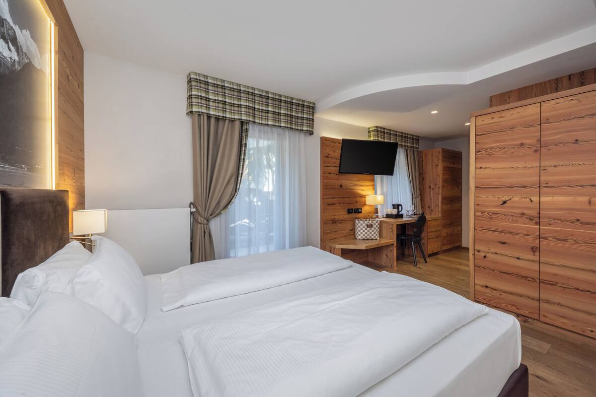 Une chambre d’hôtel avec un grand lit, un bureau avec une chaise, une télévision et un lambris en bois.