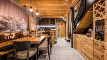 A modern kitchen with wooden cabinetry, a central island, and a dining area with a bench and chairs.