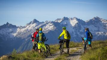 A group of mountain bikers on a gravel path with a mountainous backdrop.