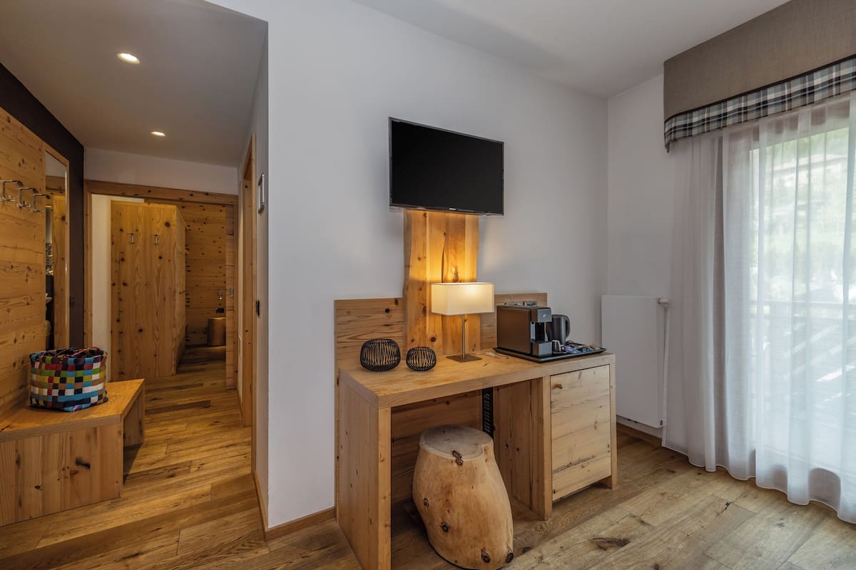 Une chambre moderne avec un bureau en bois, un téléviseur à écran plat fixé au mur, une lampe et une machine à café.