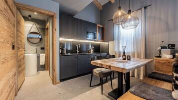 Una cocina moderna con armarios oscuros, una mesa de comedor de madera e iluminación colgante.