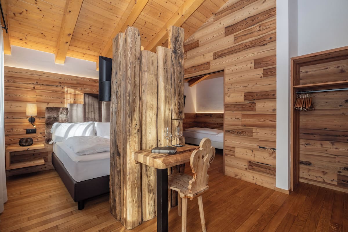 L'intérieur d'une cabane en bois, avec un lit, un bureau en bois et une chaise.