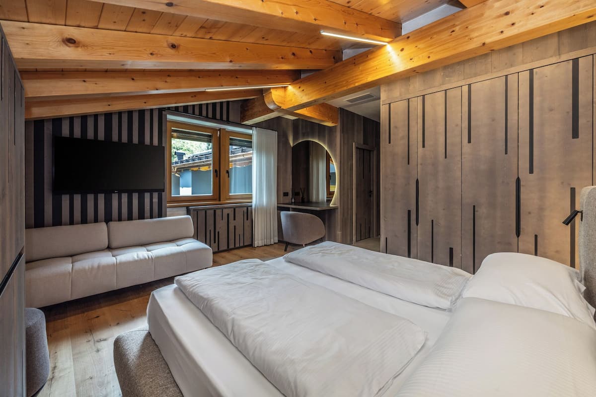 Une chambre à coucher avec un grand lit, un canapé, une télévision et un lambris en bois.