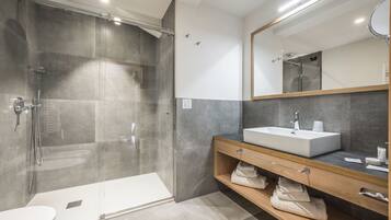 A modern bathroom with a glass-enclosed shower, a white sink, and a wooden vanity.
