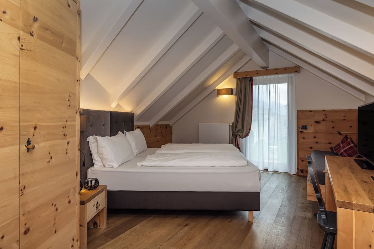 Une chambre à coucher avec un lit en bois, un bureau et une fenêtre avec des rideaux.