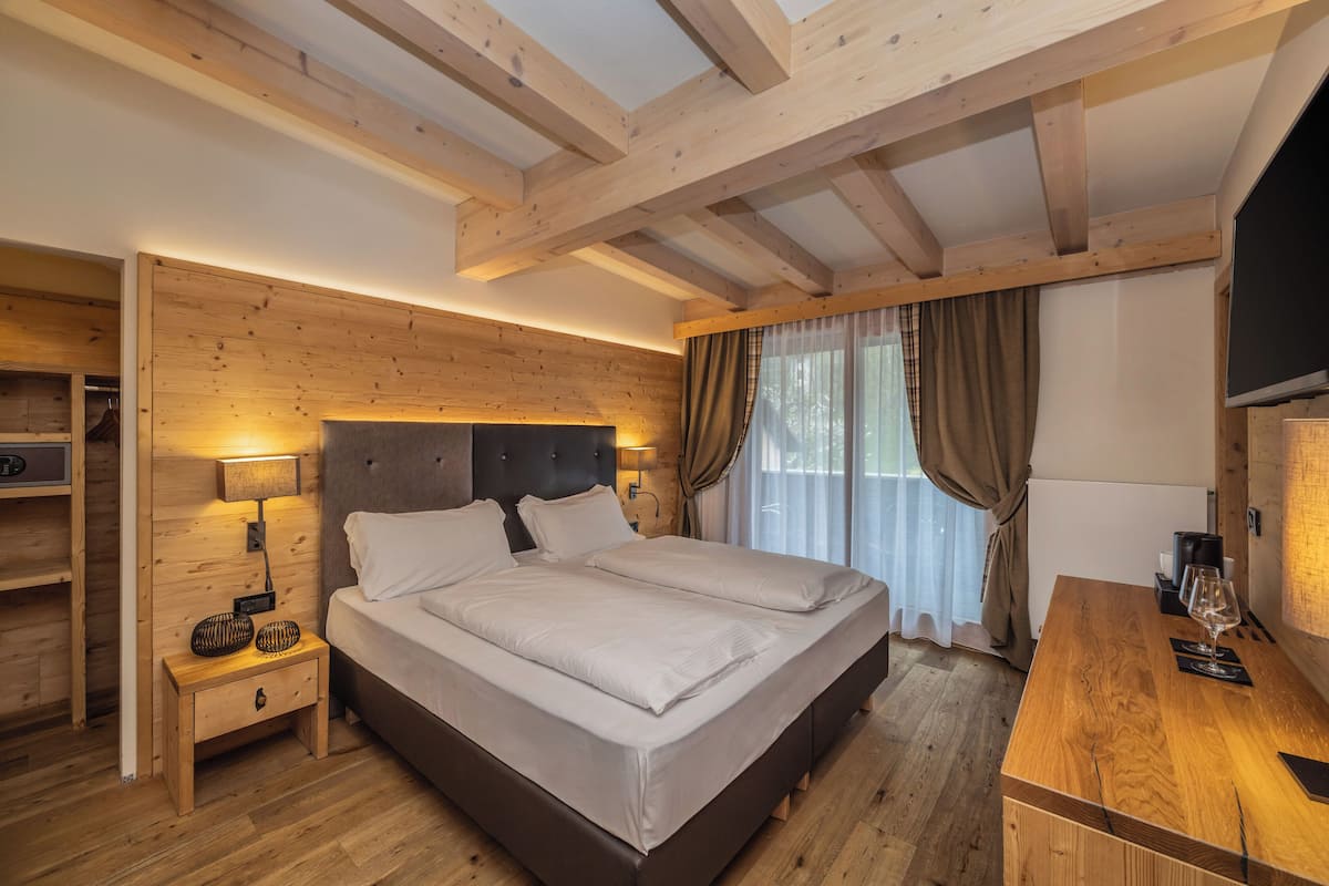 Une chambre à coucher avec un cadre en bois, comprenant un lit, des tables de chevet, un téléviseur et un bureau avec un verre.