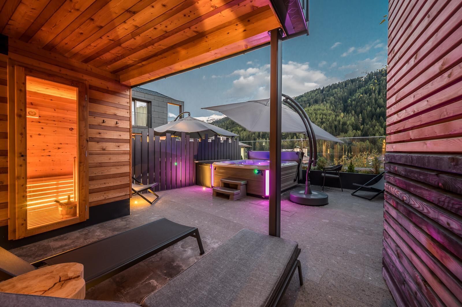 Une cabane en bois dotée d’un sauna, d’un espace extérieur aménagé et offrant une vue sur une chaîne de montagnes boisées.