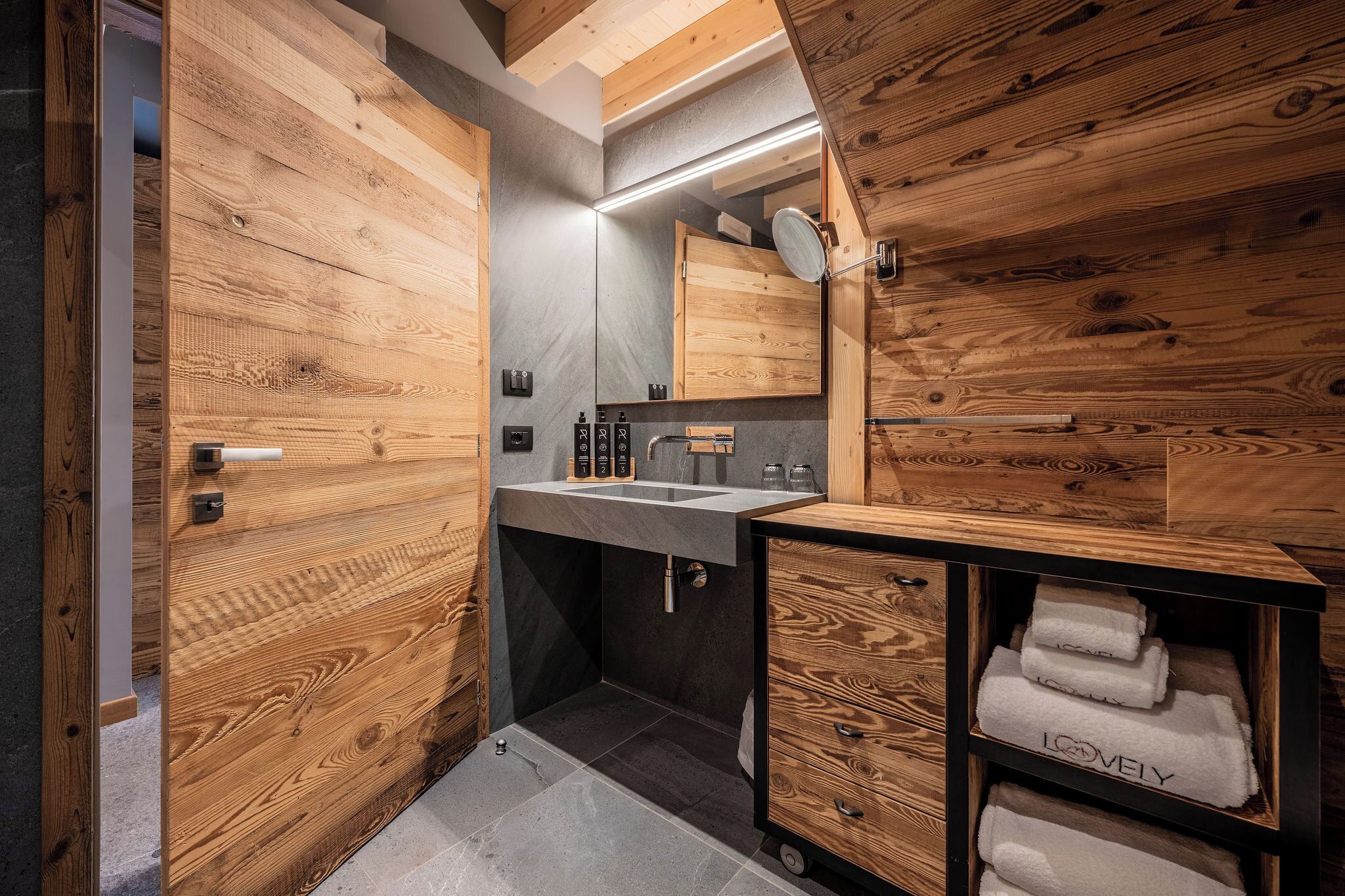 A modern bathroom with wooden walls, a sink, and a mirror.