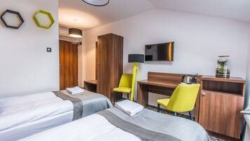 Una habitación de hotel con dos camas, un escritorio, una silla, un televisor y un armario.