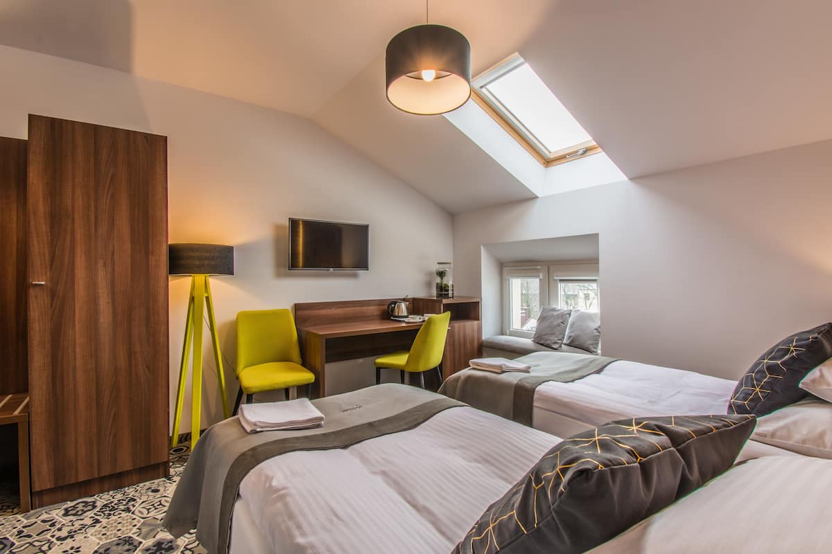 Una habitación de hotel moderna con dos camas, un escritorio, una silla y un televisor.