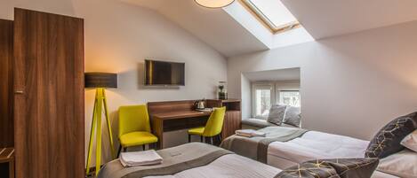 Une chambre d’hôtel moderne équipée de deux lits, d’un bureau, d’une chaise et d’une télévision.