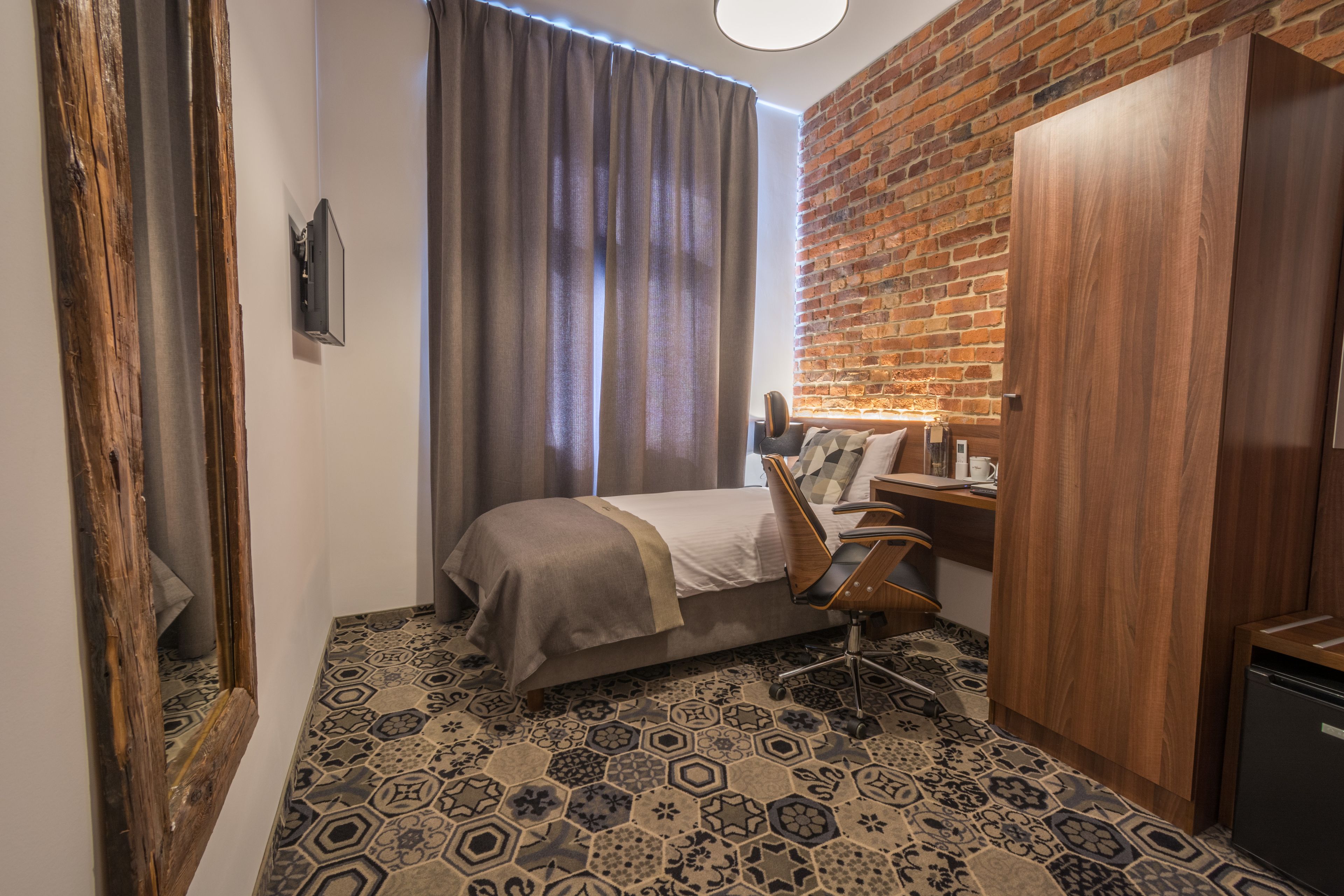 Quarto com cama, escrivaninha, cadeira, guarda-roupa e espelho.