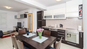 A compact kitchen with a dining area, a built-in oven, microwave, and a sink. - Apartments Carmelitta (Dubrovnik)
