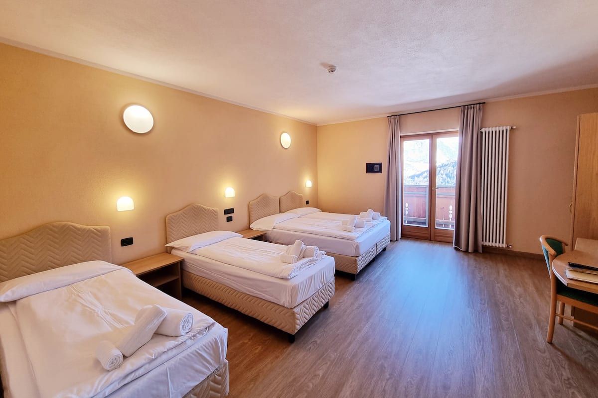 Habitación de hotel con dos camas, piso de madera y vista al exterior mediante un ventanal corredero.