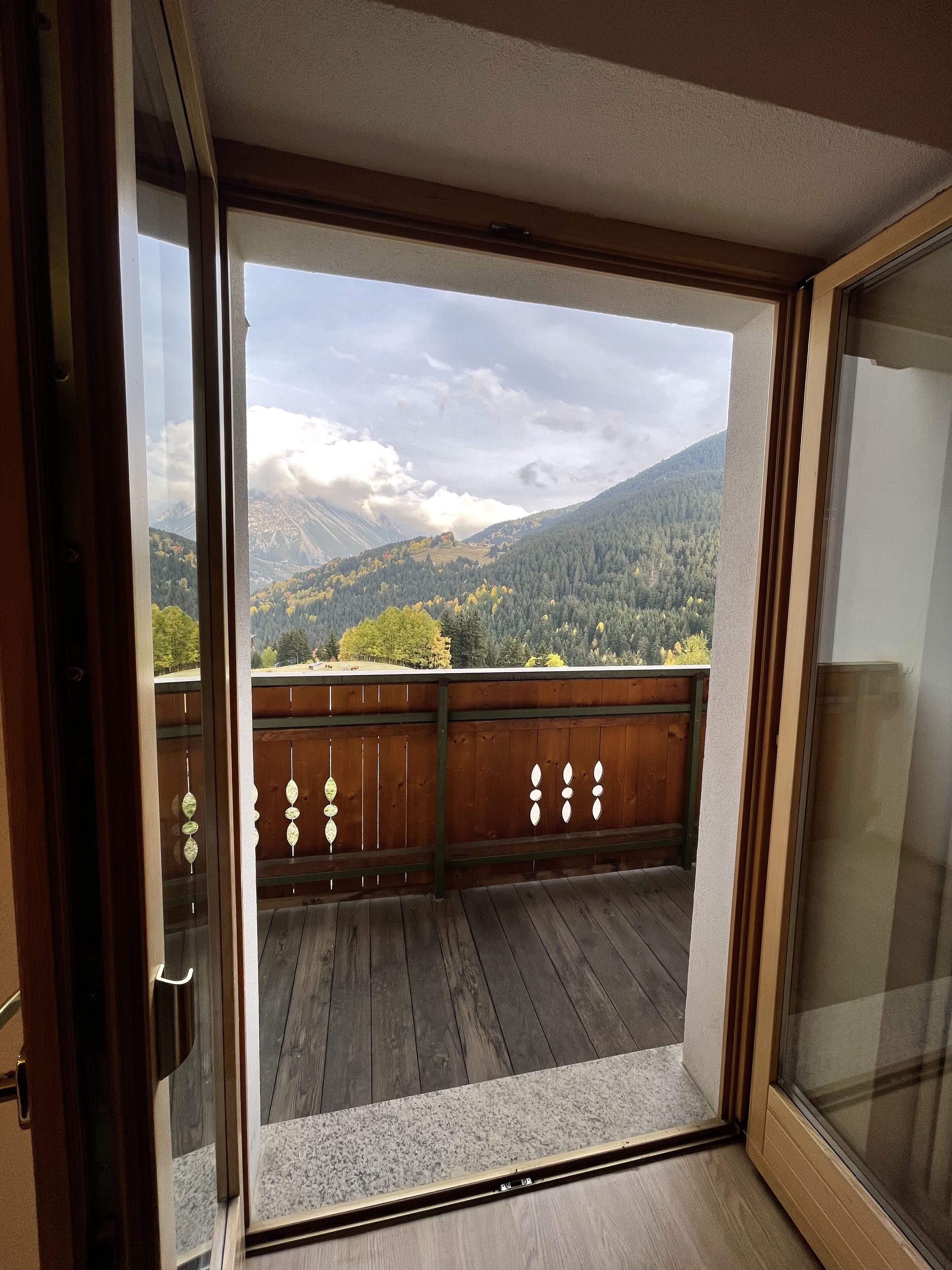 Un balcón con barandilla de madera y vistas a un paisaje montañoso.