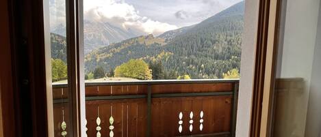 Un balcón con barandilla de madera y vistas a un paisaje montañoso.