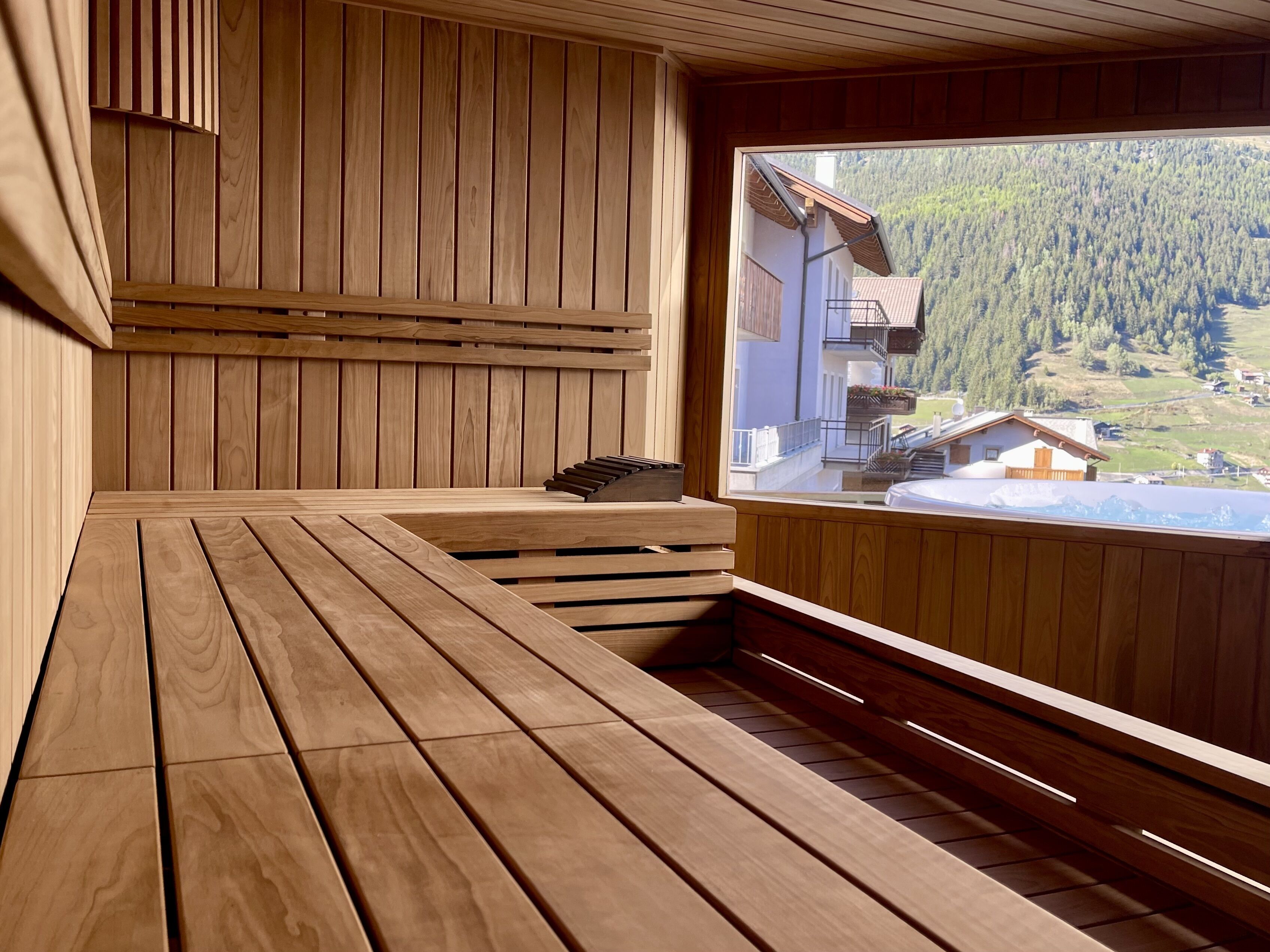 A wooden sauna with a bench and a view of a mountainous landscape.