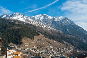 Un pueblo de montaña con picos nevados, colinas boscosas y una combinación de edificios residenciales y comerciales.