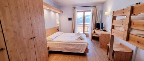 Une chambre d’hôtel avec deux lits, des meubles en bois, un bureau avec un ordinateur et une vue sur l’extérieur.