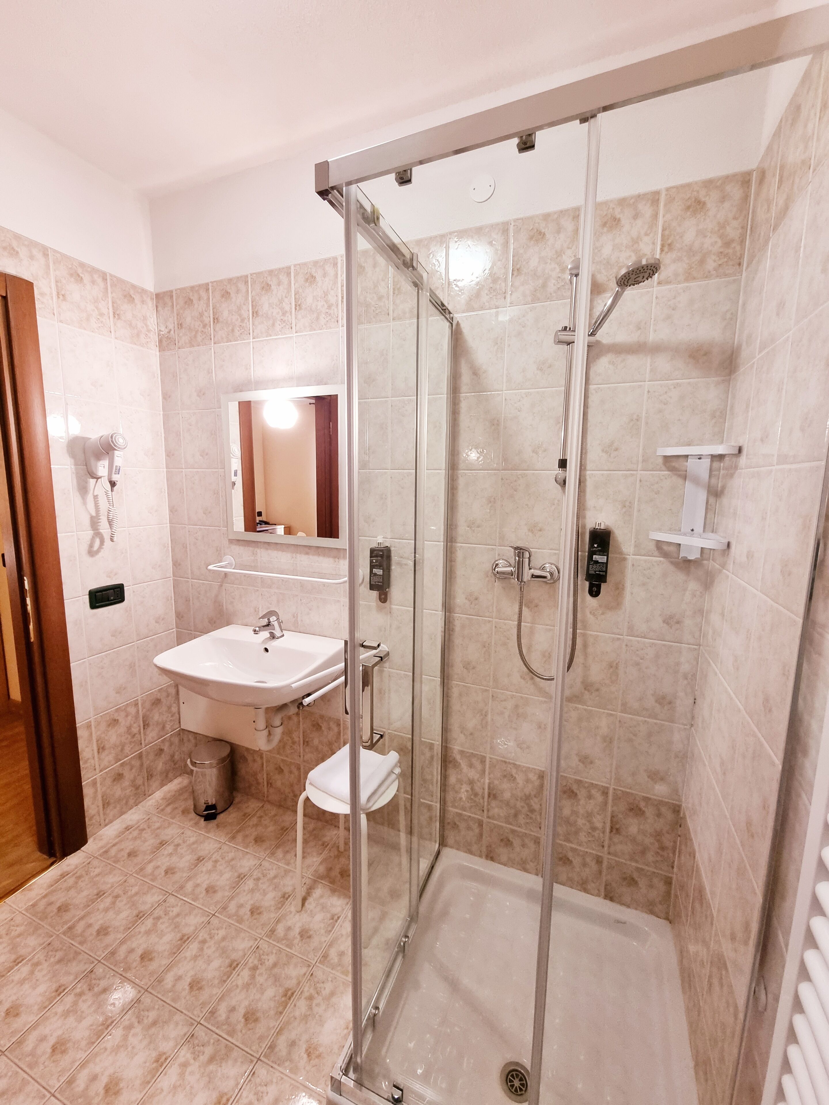 Un baño moderno con ducha acristalada, lavamanos y espejo.