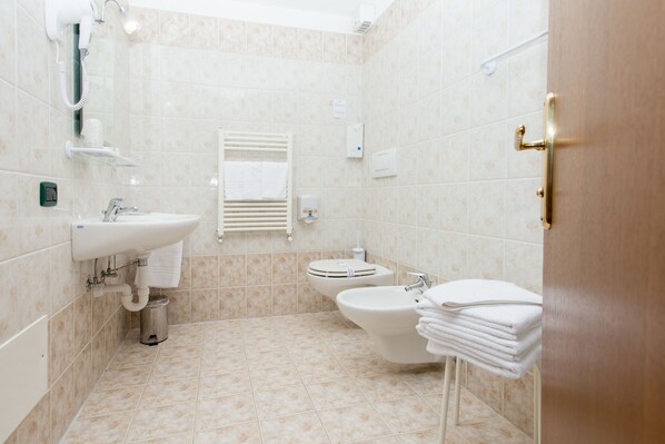 Un baño con lavamanos, bidé y toallas apiladas.
