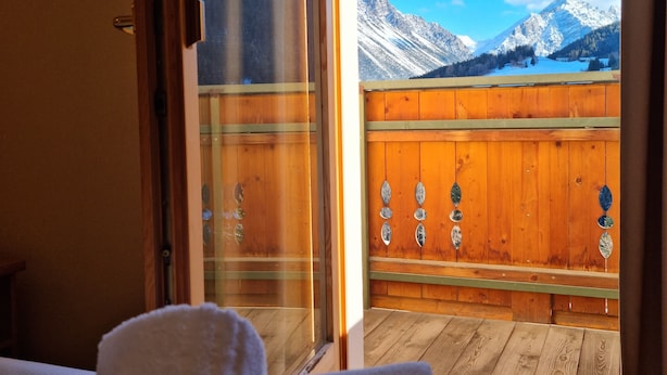 Een kamer met een houten balkon met uitzicht op een bergachtig landschap.