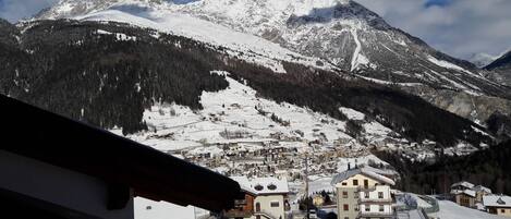 Un pueblo cubierto de nieve en la montaña, con edificios tradicionales y un telesilla.