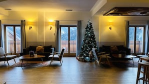 Een ruime woonkamer met een houten vloer, twee banken, een salontafel en een kerstboom.