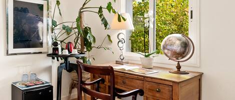 A study with a wooden desk, a globe, a lamp, and a plant.